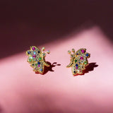 Butterfly Bloom stud earrings in solid 14K yellow gold with rainbow sapphires, green tsavorites and white diamonds against a pink background